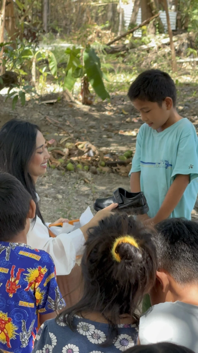 YBO Director handing shoes to children 